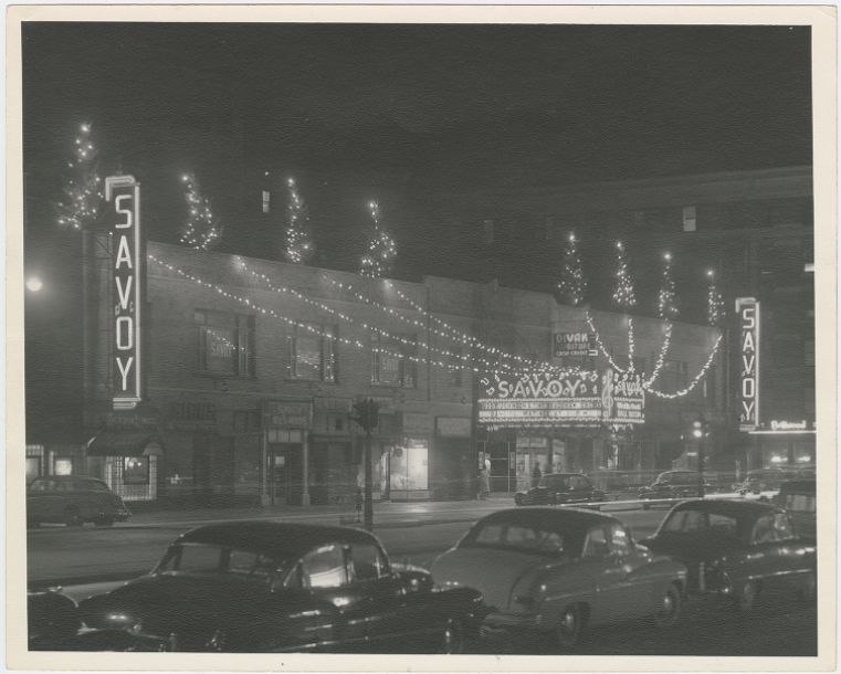 El Savoy Ballroom de noche en Lenox Avenue, con sus carteles luminosos y guirnaldas de luces a lo largo de la cuadra
